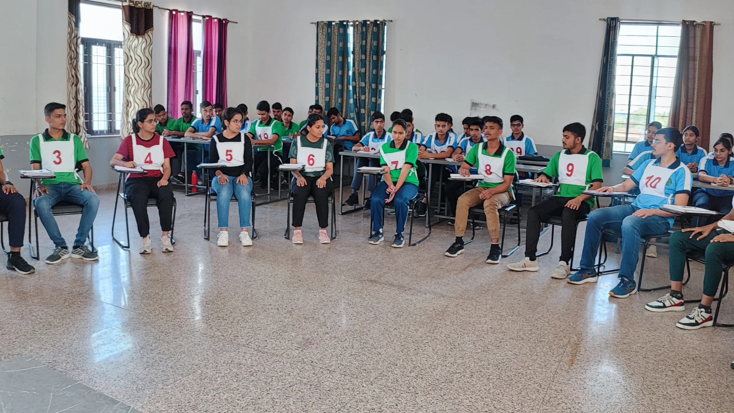 boys and girls are participating in ssb group discussion in a hall