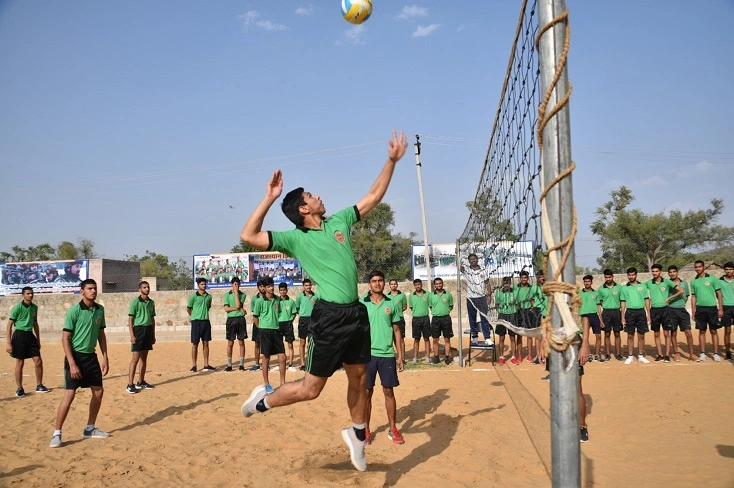 a boy jumping to hit the ball in volley ball