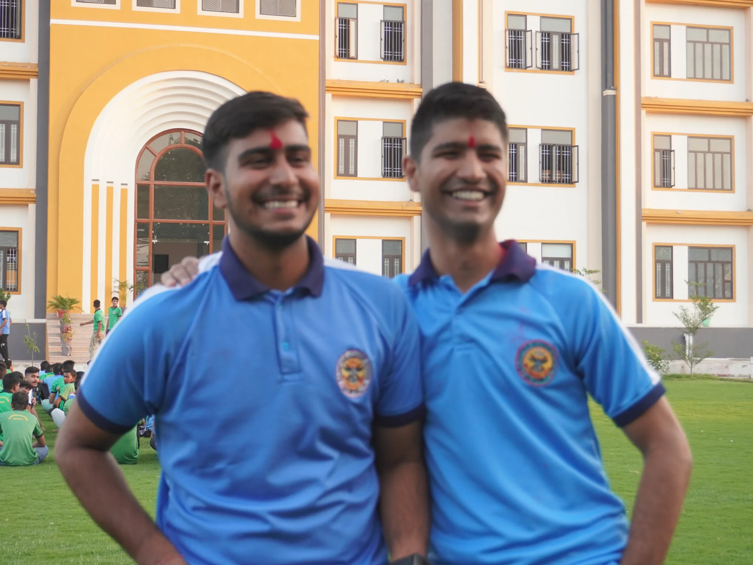 two happy boy are in blue t-shirt are standing in front of a building after success